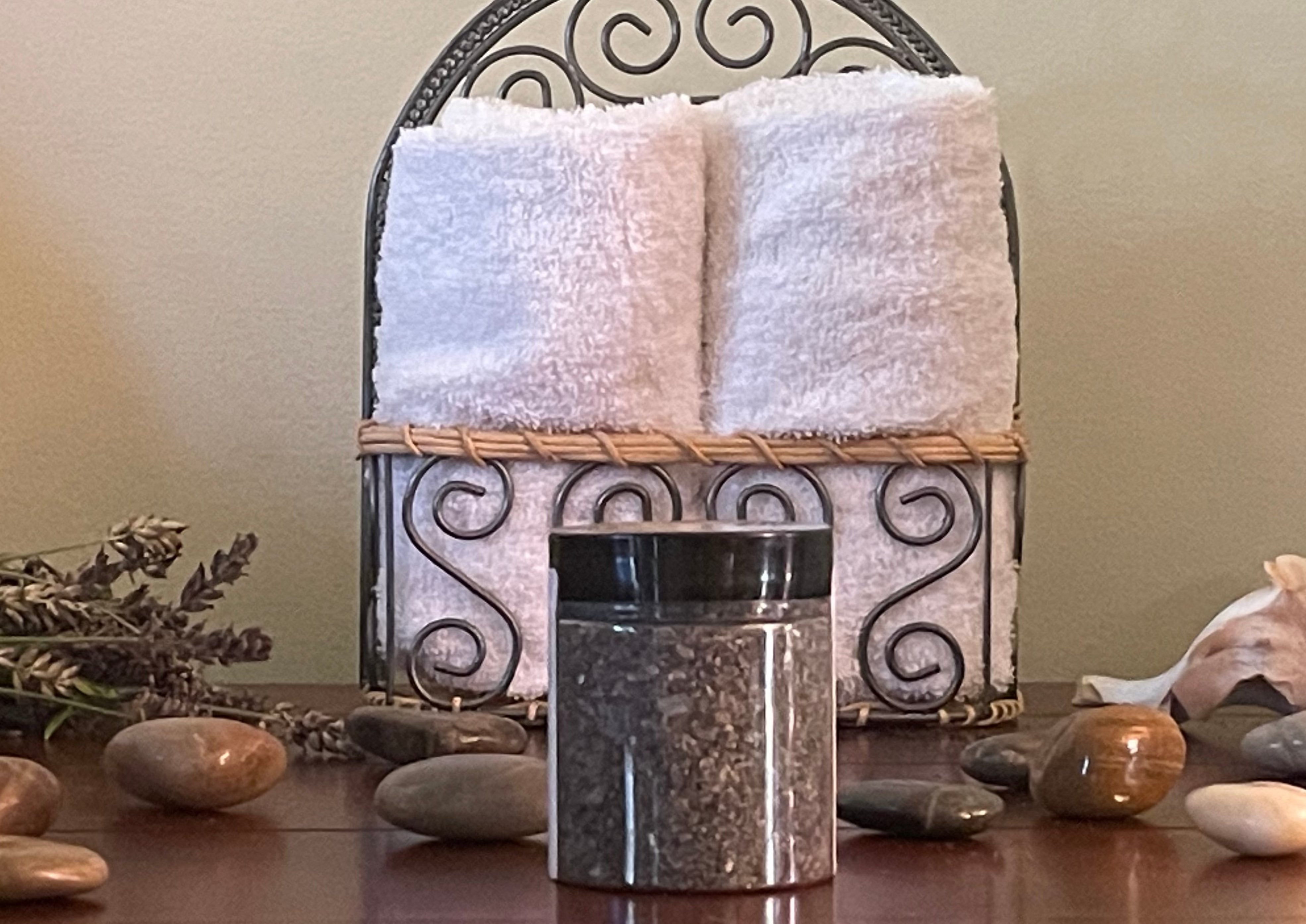 Black colored bath salts in a clear jar that has a black colored lid.