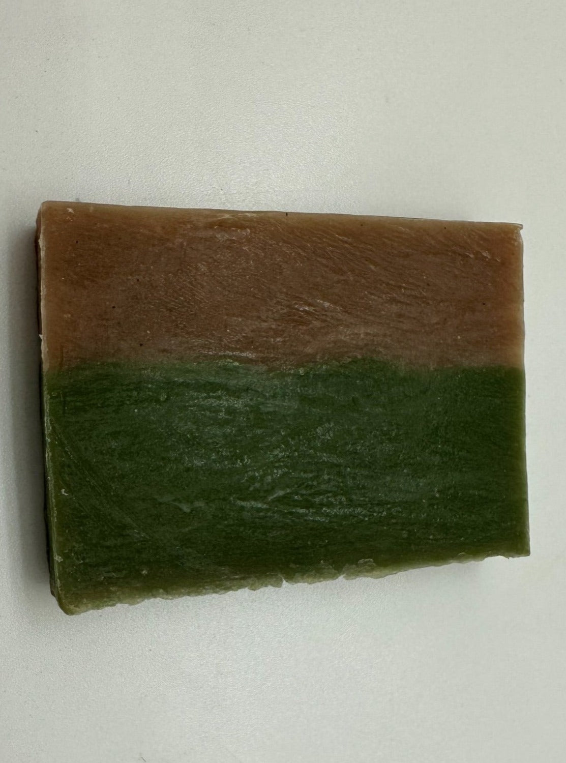 Soap bar that is colored dark green on the bottom and dark brown on the top.