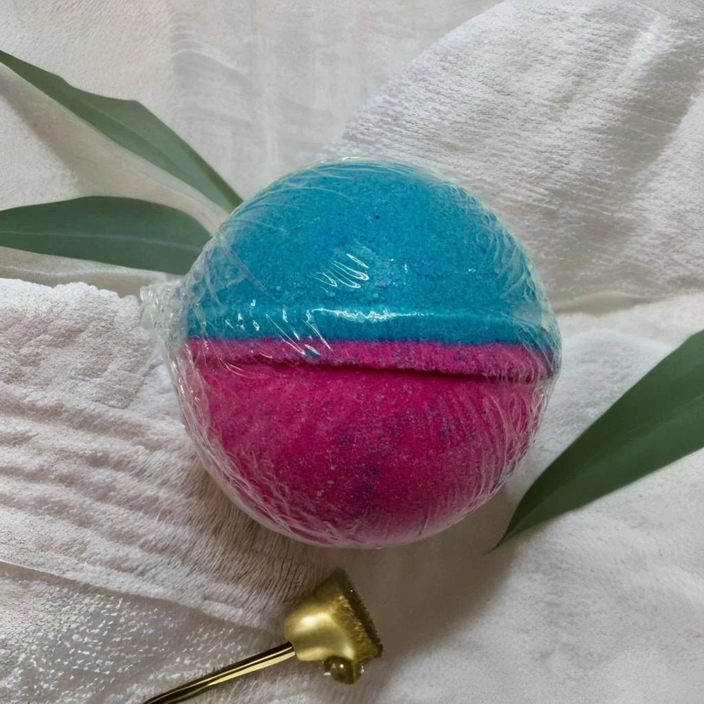 Cotton Candy Bath Bomb - MG Bath Products Bath bomb that is wrapped in plastic and has a blue colored top and a pink colored bottom.Bath Bomb