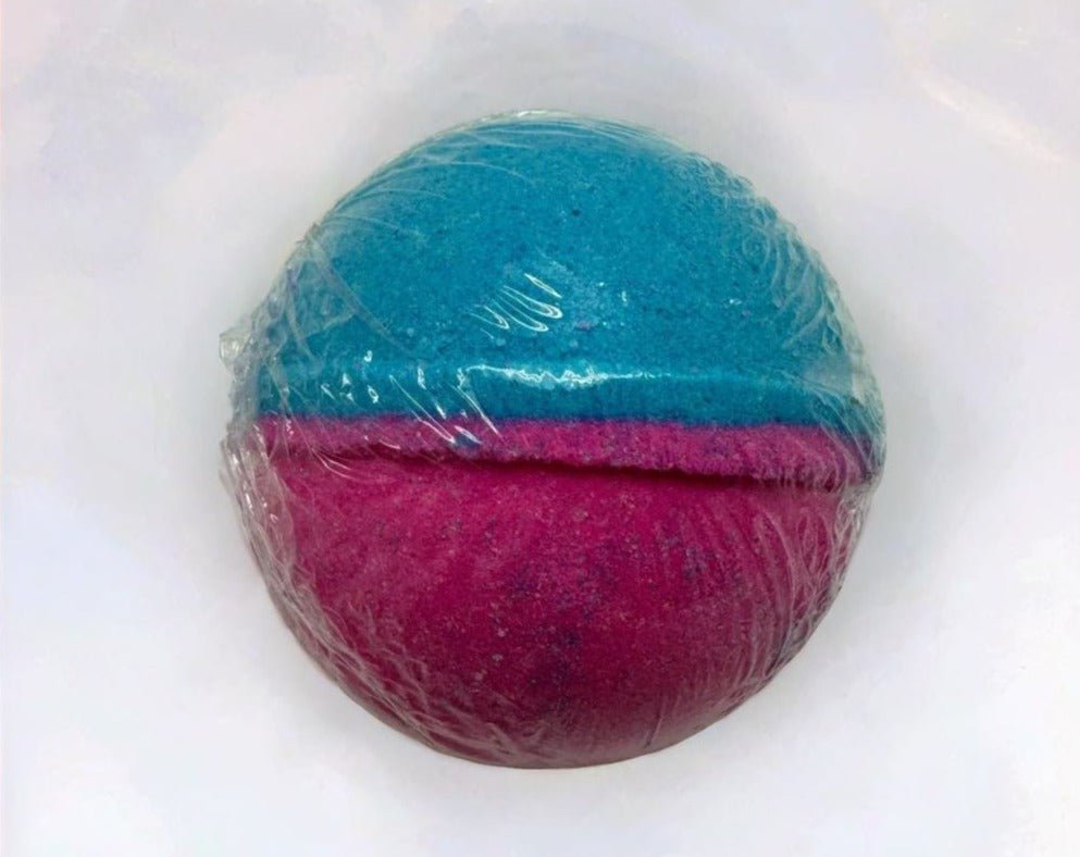 Cotton Candy Bath Bomb - MG Bath Products Bath bomb that is wrapped in plastic and has a blue colored top and a pink colored bottom.Bath Bomb