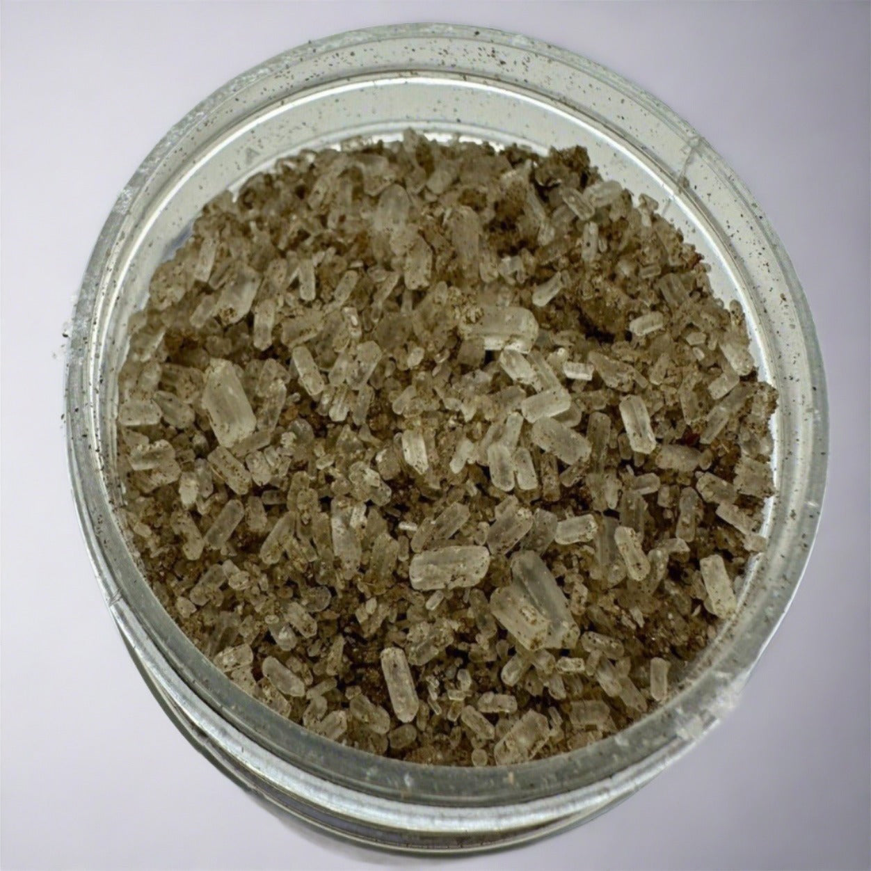Greenish brown colored bath salts in an opened jar