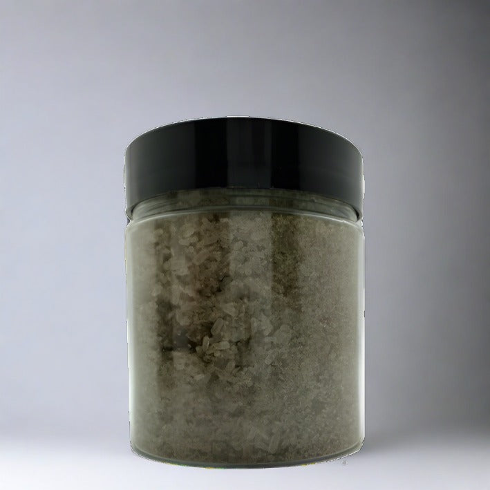 Greenish brown colored bath salts in a clear jar that has a black lid.