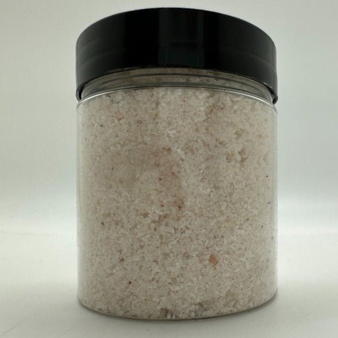 White colored bath salts in a clear jar that has a black lid.